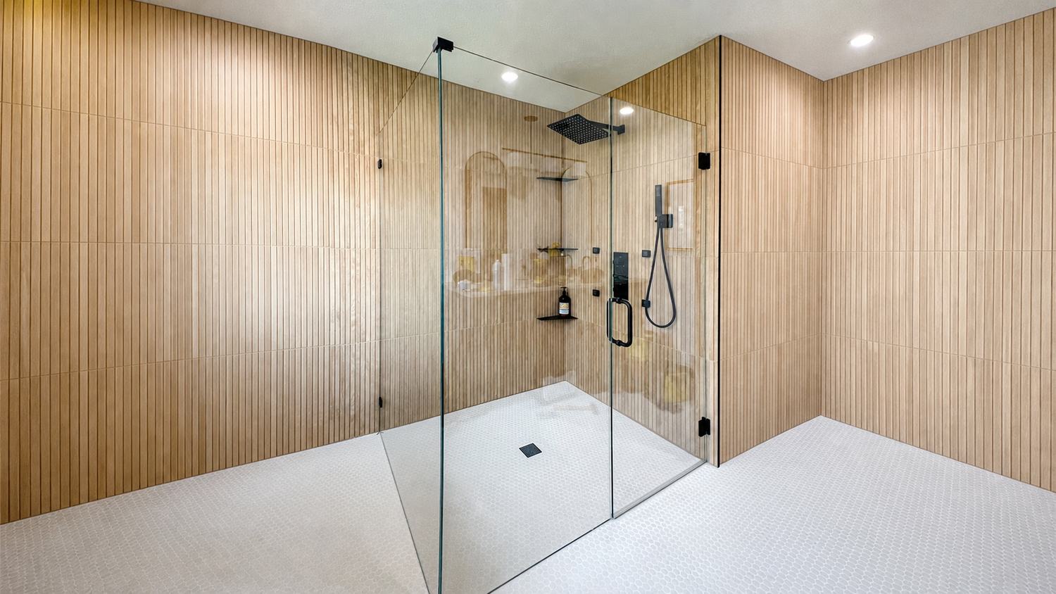Custom frameless shower enclosure with black hardware and wood slat tile
