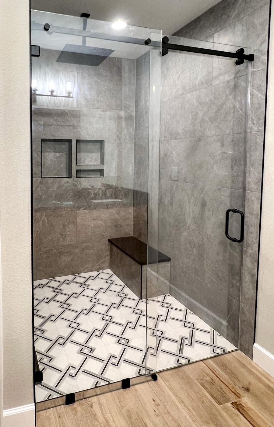 Frameless barn style sliding shower door with matte black hardware and bench