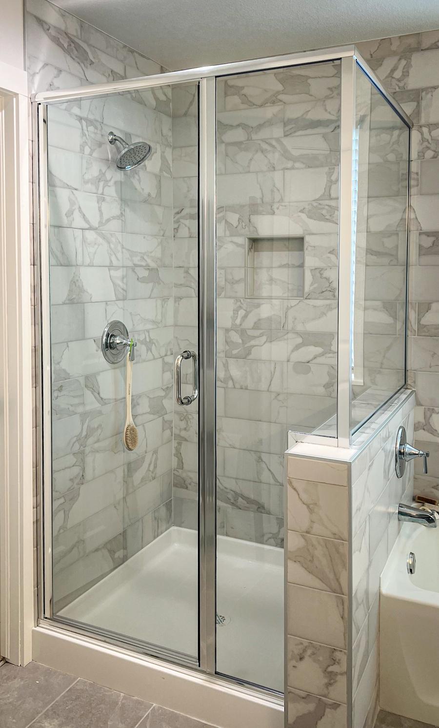 Semi-frameless swinging shower door with chrome framing and half wall