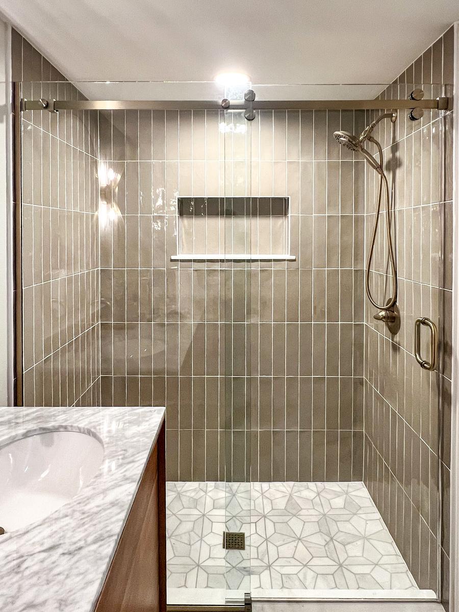 Frameless barn style sliding shower door with brushed brass hardware