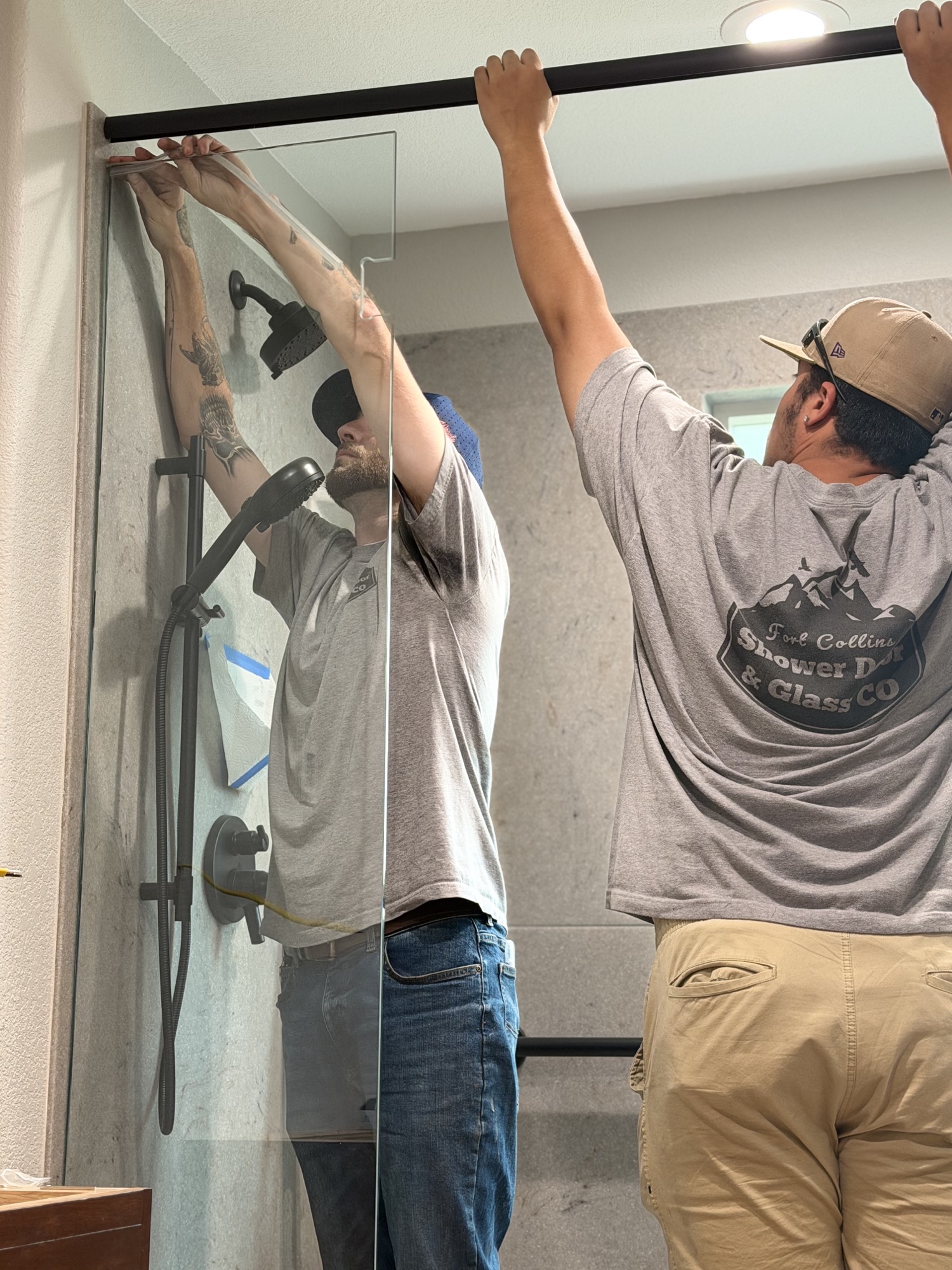 Two Fort Collins Shower Door and Glass installers fitting the header on a custom glass shower enclosure